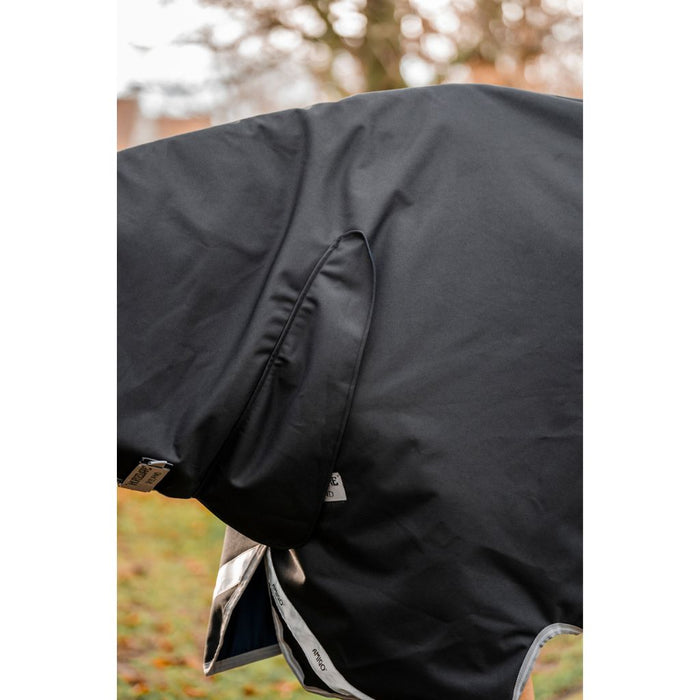 Close-up of a black horse blanket with a blurred outdoor background