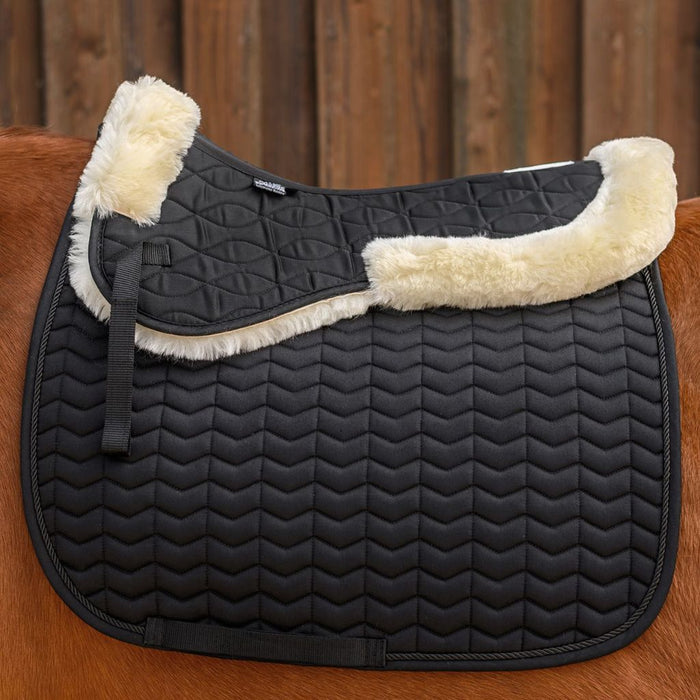 Black quilted saddle pad with cream fur trim on a chestnut horse.